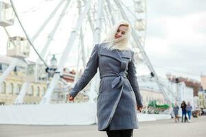 Jeune femme portant chapeau en marchant en plein air sur le ville rue près ferris roue souriant joyeux. photo