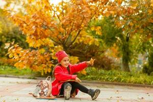 élève de primaire école avec livre dans main. fille avec sac à dos près bâtiment en plein air. début de cours. premier journée de automne. photo