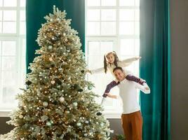 content père et le sien peu fille décorer le Noël arbre à maison. photo