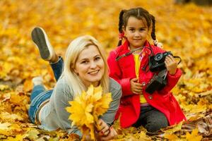 mère et fille mensonge sur le feuilles à le l'automne parc. photo