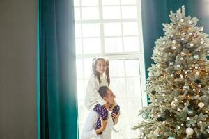 content Jeune père et le sien fille à Accueil avec Noël arbre photo