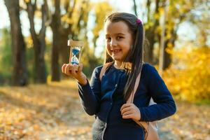 peu écolière près le école. préscolaire enfant avec une sac à dos sur le sien premier journée à école ou Jardin d'enfants. retour à école. enfant éducation. l'automne photo