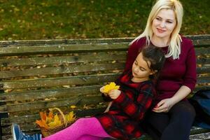 mère et fille sur une banc dans l'automne parc photo