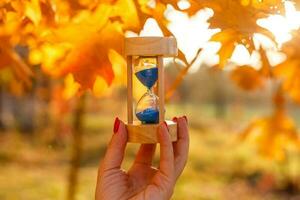 l'automne temps thème, sablier sur déchue feuilles dans divers couleurs avec copie espace. photo