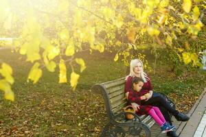 content mère et fille embrassement sur une banc dans un l'automne parc photo