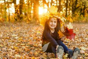 l'automne saison loisirs. atmosphère de l'automne. adorable souriant écolière l'automne feuillage Contexte. bien ambiance. content enfant. Bienvenue octobre. uni avec la nature. peu enfant marcher dans l'automne parc. photo