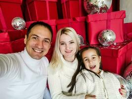 Noël. famille. technologie. vue sur le téléphone intelligent. papa, maman et fille à la recherche à caméra et souriant tandis que Faire selfie photo