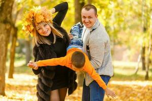 Jeune famille ayant amusement dans le l'automne parc avec le sien fils. photo