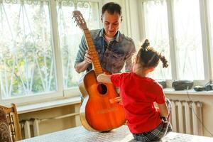 fermer homme main en changeant cordes sur le sien vieux acoustique guitare. photo