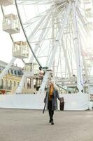 Jeune femme en marchant en plein air sur le ville rue près ferris roue souriant joyeux. photo