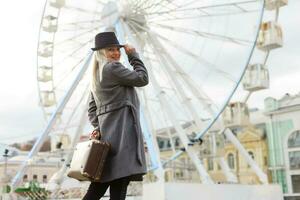 Jeune femme portant chapeau en marchant en plein air sur le ville rue près ferris roue souriant joyeux. photo