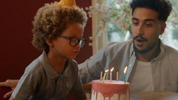 Garçon soufflant des bougies sur le gâteau avec la famille en regardant photo