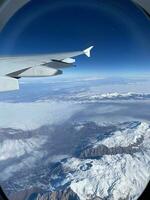 vue de avion fenêtre de enneigé montagnes dans l'hiver. photo