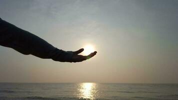 silhouette de main atteindre en dehors à le mer avec le coucher du soleil Contexte photo