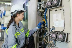 électricité ingénieur femelle travail vérifier un service haute Tension électrique armoire. ouvrier réparation électrique poussée problème problème dans industrie usine. photo