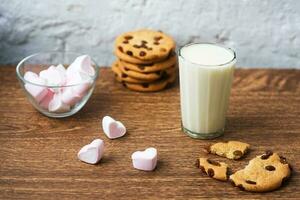 biscuits aux puces faits maison avec du lait et de la guimauve à l'air sur une serviette de cuisine et une table en bois. bonjour. petit-déjeuner photo