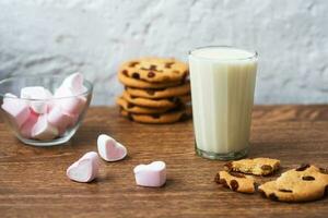 biscuits aux puces faits maison avec du lait et de la guimauve à l'air sur une serviette de cuisine et une table en bois. bonjour. petit-déjeuner photo