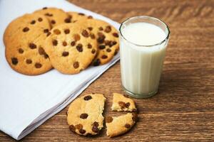 biscuits parfumés, savoureux et faits maison avec des raisins secs et un verre de lait frais sur le torchon blanc photo