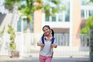 retour à école. mignonne asiatique enfant fille avec une sac à dos fonctionnement et Aller à école avec amusement photo