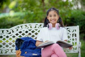 retour à école. asiatique fille en train de lire une livre. primaire école élèves après Des classes apprentissage devoirs. photo