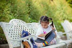 retour à école. asiatique fille en train de lire une livre. primaire école élèves après Des classes apprentissage devoirs. photo