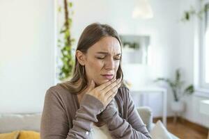 dent douleur et dentisterie. Jeune femme Souffrance de terrible fort les dents douleur, émouvant joue avec main. femelle sentiment douloureux mal aux dents. dentaire se soucier et santé concept. photo