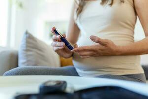 tester la glycémie pour le diabète chez la femme enceinte avec glucomètre. une goutte de sang rouge sur le doigt prêt à mesurer le niveau de sucre. gros plan sur un doigt masculin avec une goutte de sang et une bande de test photo