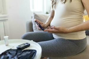 tester la glycémie pour le diabète chez la femme enceinte avec glucomètre. une goutte de sang rouge sur le doigt prêt à mesurer le niveau de sucre. gros plan sur un doigt masculin avec une goutte de sang et une bande de test photo