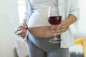 fumeur et de l'alcool grossesse.femme sur une longue grossesse en buvant de l'alcool et fumeur cigarettes.problèmes de alcoolisme et le période de palier une enfant.danger de perdant une bébé, fausse-couche. alcoolique photo