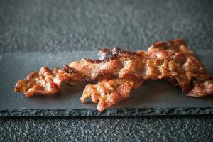 frit Bacon bandes sur le pierre foncé planche photo