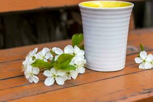 une tasse de café sur une table en bois rustique sombre et usée. la composition est ornée d'une brindille à fleurs blanches. fleurs de cerisier. mise au point sélective. photo