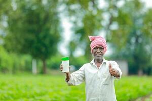 Indien content agriculteur en portant vide bouteille dans mains, content agriculteur montrant blanc bouteille photo