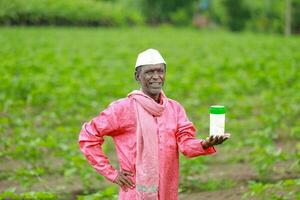 Indien content agriculteur en portant vide bouteille dans mains, content agriculteur montrant blanc bouteille photo