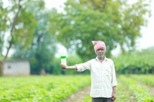 Indien content agriculteur en portant vide bouteille dans mains, content agriculteur montrant blanc bouteille photo