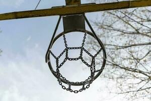 un le fer basketball cerceau dans le ouvert air contre une bleu ciel Contexte. basketball cerceau avec le fer net photo