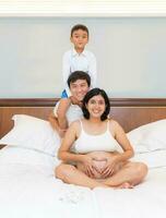 Jeune Enceinte femme et fils forme une chaud famille. photo