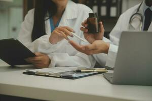 médecin confiant tenant une bouteille de pilules et écrivant tout en parlant avec un patient âgé et en examinant ses médicaments dans la salle de bureau. photo