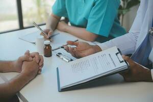 médical équipe ayant une réunion avec médecins dans blanc laboratoire manteaux et chirurgical gommages assise à une table discuter une les patients records, succès médical santé se soucier, médicament médecins travail concept photo