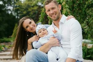 portrait de une de bonne humeur content Jeune famille avec une peu fils repos dans le parc dans printemps photo