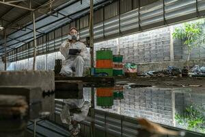 urgence la pollution usine concept. femelle chimiste portant ppe et gaz masque inspecter pétrole sur usine sol photo