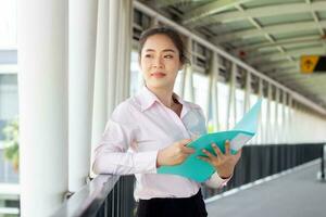 magnifique asiatique femme dans costume en portant dossier sur couloir. photo