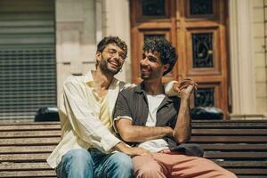 Hommes séance sur une banc dans le ville embrasser ang étreindre chaque autre photo