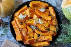 tranches de citrouille au four dans une poêle avec des herbes et de l'ail photo