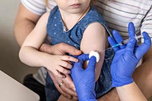 une petite fille avec son père dans le cabinet du médecin de la clinique se fait vacciner contre le coronavirus.le concept de vaccination, immunisation, prévention contre covid-19.