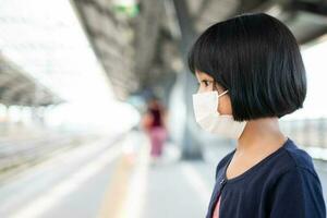 petite fille avec masque chirurgical protection du visage grippe et épidémie de virus dans les transports en commun skytrain ou métro. concept de nouveau mode de vie normal, utilisant les transports en commun pour se rendre à l'école. photo