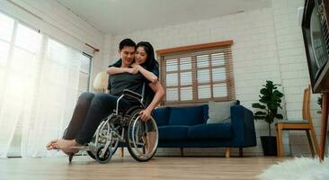 un homme asiatique en fauteuil roulant à la maison après un accident de voiture et sa femme pour l'encourager. le concept de soins mutuels et les nouvelles technologies ont fait des personnes handicapées l'égalité dans la société. photo