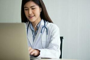 une femme médecin asiatique visite en ligne un patient sur l'application internet et écoute les symptômes et explique comment traiter la maladie initiale, concept de technologie médicale. photo