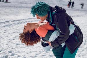 un couple amoureux se tient debout et s'amuse dans la neige par une journée d'hiver ensoleillée. photo
