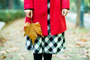 femme dans vêtements d'extérieur permanent avec érable feuille photo