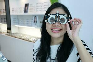 thaïlandais Dame portant lunettes à l'intérieur le clinique, femme dans optique photo